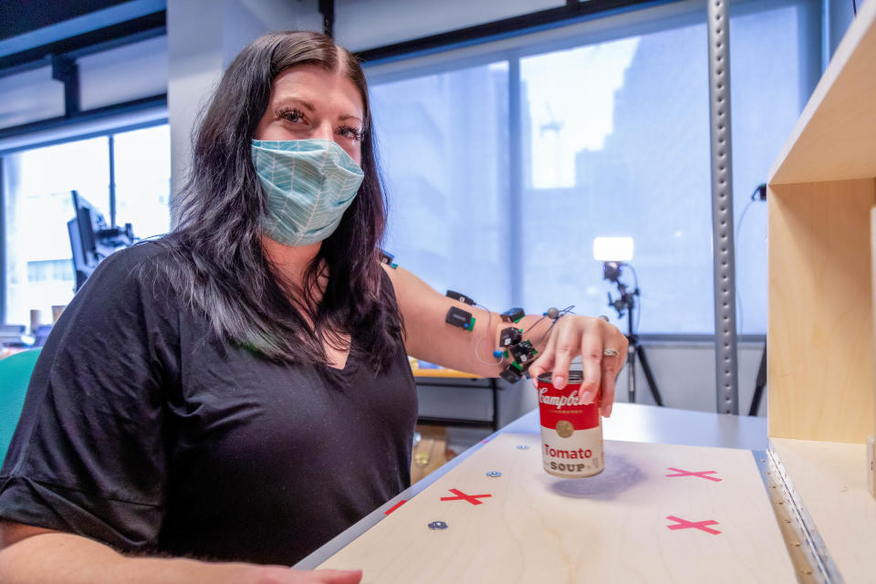 Research participant Heather Rendulic holds a can of soup with her affected arm at Rehab Neural Engineering Labs at the University of Pittsburgh.