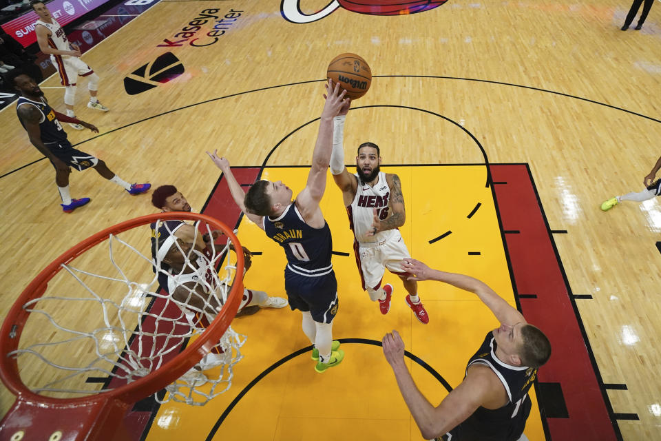 Denver Nuggets guard Christian Braun (0) blocks the shot of of Miami Heat forward Caleb Martin (16) during the second half in Game 4 of the basketball NBA Finals, Friday, June 9, 2023, in Miami. (Kyle Terada/Pool Photo via AP)