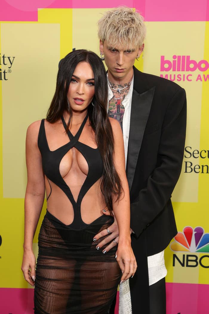 MGK holding onto Megan's waist as they pose for photos on a red carpet