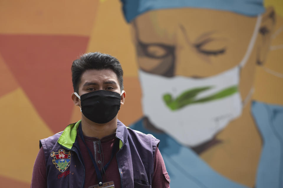 Urban artist Kevin Perez poses for photos in front of his mural in honor of health workers who assist COVID-19 patients in the country's hospitals, near La Verbena cemetery in Guatemala City, Wednesday, June 24, 2020. (AP Photo/Moises Castillo)