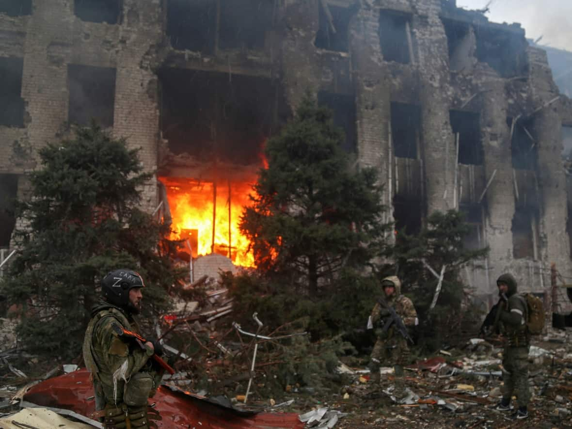 Pro-Russian troops, including fighters with the Chechen special forces unit, stand in front of the destroyed administration building of the Azovstal Iron and Steel Works in Mariupol, Ukraine on April 21. (Chingis Kondarov/Reuters - image credit)