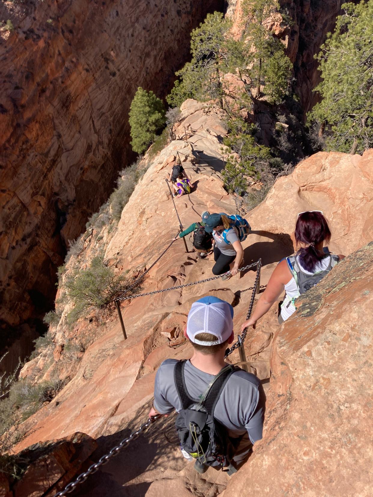 Hikers face a steep climb on the Angels Landing trail in Zion National Park on April 1, 2022. Metal chains built into the red rock help guide their way and get them down safely.