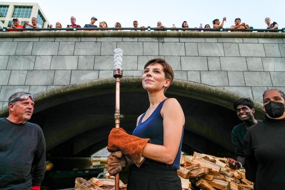 Torch in hand and pine logs stacked behind her, Russo and the other volunteers on her boat get ready to tend the braziers at WaterFire.