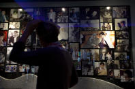 In this photo taken Wednesday, April 16, 2014, a member of the Israeli and foreigner's group tour, that is organized by IPCRI, an Israeli Palestinian group promoting co-existence, tours by memorial photos of late Mahmoud Darwish including one with late Palestinian leader Yasser Arafat, center right, during their visit to a museum dedicated to national poet Mahmoud Darwish, at the West Bank city of Ramallah. This bustling center of Palestinian life is just a 20-minute drive from Jerusalem, but for Israelis it might as well be on the other side of the world. (AP Photo/Nasser Nasser)