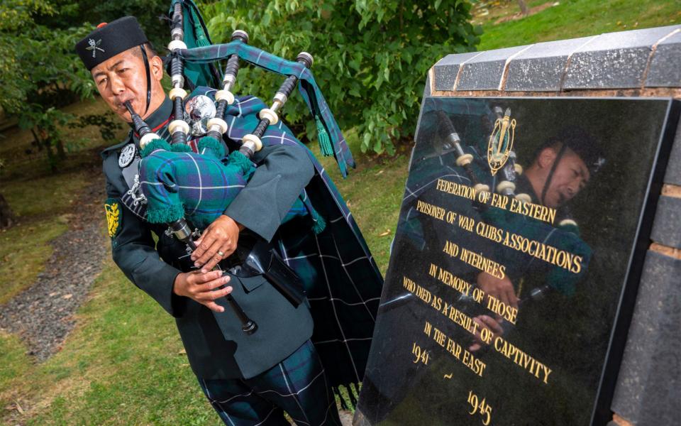 A lone piper plays at the VJ Day commemorations - PA