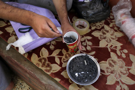 Hudhayfa al-Shahad fills a paper cup with charcoal in Idlib, Syria September 3, 2018. Picture taken September 3, 2018. REUTERS/Khalil Ashawi