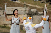 Olympics - Dress Rehearsal - Lighting Ceremony of the Olympic Flame Pyeongchang 2018 - Ancient Olympia, Olympia, Greece - October 23, 2017 Greek actress Katerina Lehou, playing the role of High Priestess, passes an olive branch to the first torchbearer, Greek cross country skiing athlete Apostolos Aggelis, during the dress rehearsal for the Olympic flame lighting ceremony for the Pyeongchang 2018 Winter Olympic Games at the site of ancient Olympia in Greece REUTERS/Alkis Konstantinidis