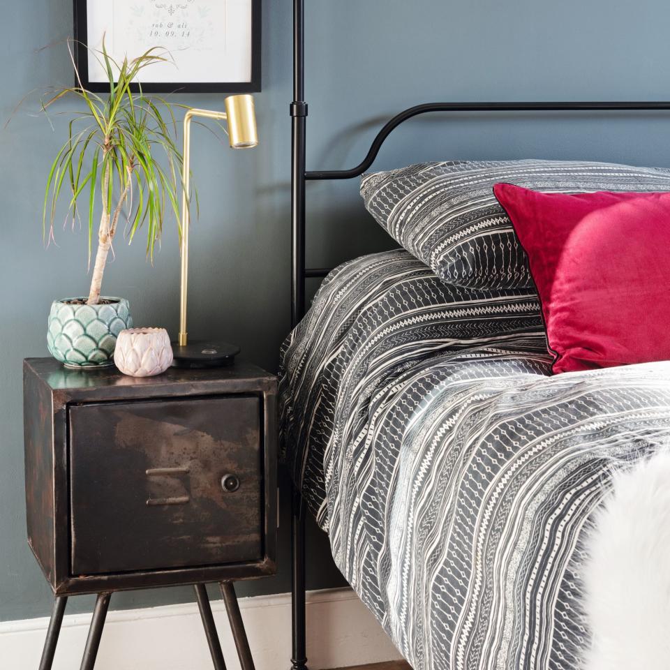 vintage bedside table next to double bed with grey bedding