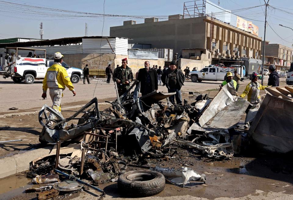 People and security forces inspect the site of a car bomb attack in Baghdad's Karrada neighborhood, Iraq, Thursday, Feb. 6, 2014. Iraqi officials say a string of car bombings has hit commercial areas in Baghdad, killing and wounding scores of people. (AP Photo/Khalid Mohammed)