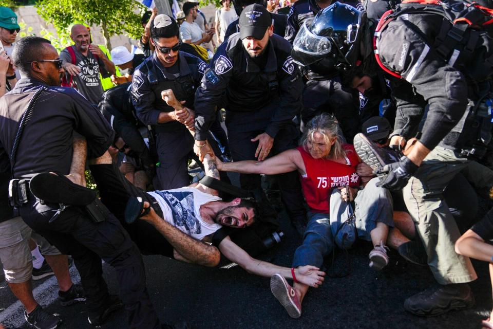 A man and a woman shout out while trying to hold on to one another as Israeli police disperse demonstrators.