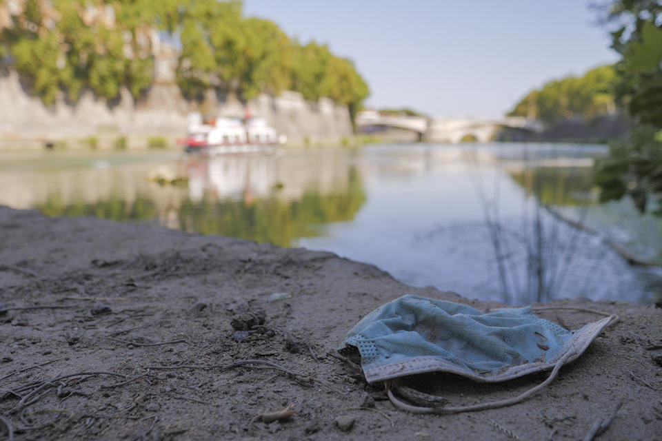 A protective mask is seen on the ground on Rome's Tiber river banks, in Rome, Wednesday, Aug. 12, 2020. Italy produced 10% less garbage during its coronavirus lockdown, but environmentalists warn that increased reliance on disposable masks and packaging is imperiling efforts to curb single-use plastics that end up in oceans and seas. (AP Photo/Paolo Santalucia)