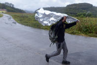 A migrant man uses thermal sheeting to protect himself from a heavy rain while walking on a road outside Velika Kladusa, Bosnia, Saturday, Sept. 26, 2020. (AP Photo/Kemal Softic)