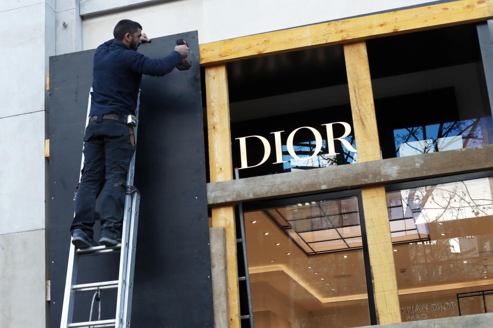 FILE - In this Friday, Nov. 30, 2018 file picture, a worker reinforces store windows on the famed Champs Elysees avenue to prepare for an expected protest by the "yellow jackets" on Saturday as a protest last weekend degenerated into violence, in Paris. One year and a half after he came into power, Macron is facing violent protests over rising taxes, high cost of living and his policies are criticized as favoring the rich. (AP Photo/Thibault Camus, File)