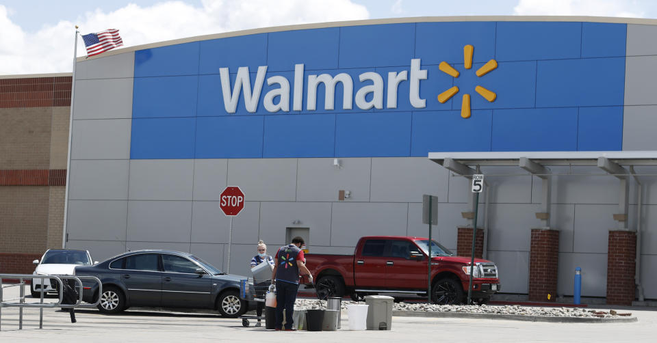 Workers sanitize items outside a Walmart that has been closed following the deaths of three people connected to the store after they were infected with the new coronavirus and at least six more employees have tested positive for COVID-19, Friday, April 24, 2020, in Aurora, Colo. (AP Photo/David Zalubowski)