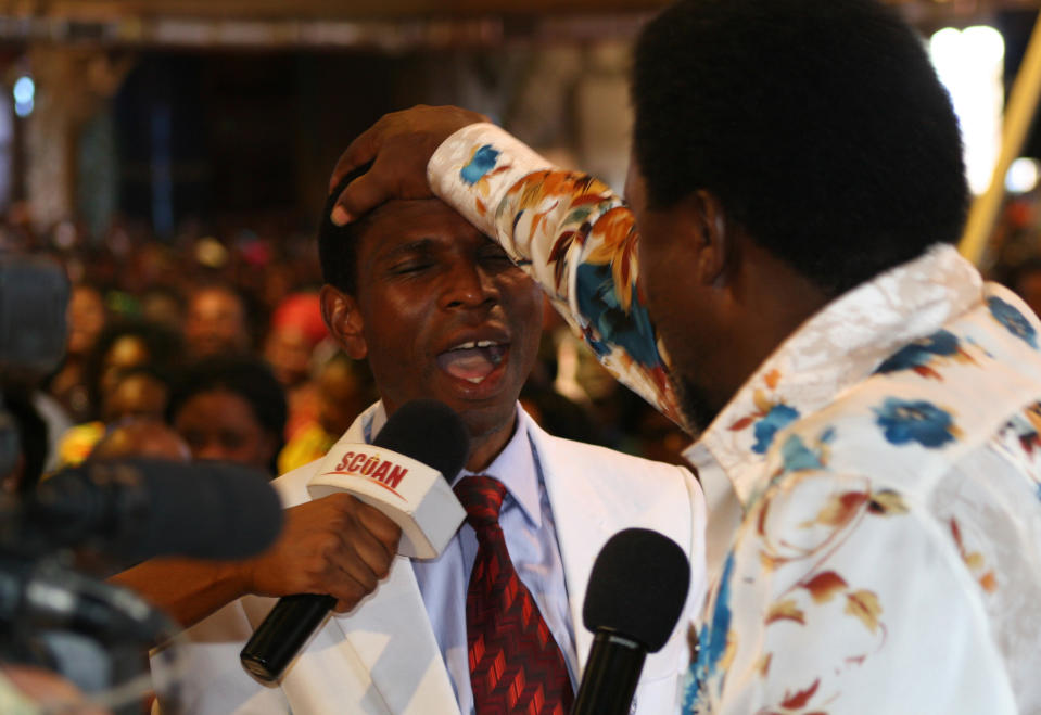 FILE - In this Sunday, Sept. 15, 2013 file photo, T.B. Joshua lays his hand on the head of a worshipper during a service at the Synagogue, Church of All Nations, in Lagos Nigeria. T.B. Joshua's Synagogue, Church of All Nations has branches around the world, and a recent YouTube video even credits him with predicting the disappearance of Malaysian Airlines Flight MH370. Joshua is one of the best-known preachers in Africa and among the most profitable in Nigeria, the go-to faith healer and spiritual guide for leaders such as the late Ghanaian president John Atta Mills, Malawian president Joyce Banda and former Zimbabwean prime minister Morgan Tsvangirai. The man who says he comes from the poor village of Arigidi is worth between $10 and $15 million based on assets, according to Forbes magazine, which in 2011 estimated his personal wealth. The church holds some 15,000 people with outside tents for the overflow and Sunday services are beamed worldwide. Yet critics say this wildly popular televangelist hinders efforts to curtail the spread of HIV and tuberculosis with testimonies by church-goers that faith and his holy water can cure both. He is also accused of taking advantage of his followers and tightly controlling those closest to him, who call him "Daddy."(AP Photo/Carley Petesch, file)