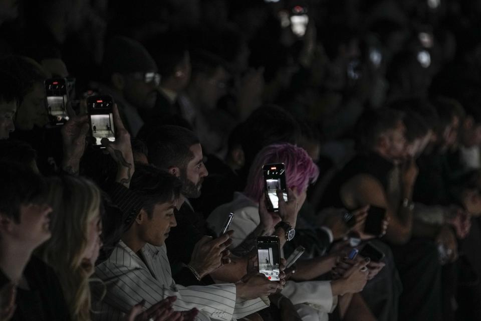 Spectators use their cell phones to record the men's Dolce & Gabbana Fall-Winter 2024-2025 collection, that was presented in Milan, Italy, Saturday, Jan. 13, 2024. (AP Photo/Luca Bruno).