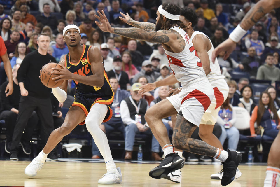 Oklahoma City Thunder guard Shai Gilgeous-Alexander, left, looks to shoot over Toronto Raptors guard Gary Trent Jr., right, in the first half of an NBA basketball game, Sunday, Feb. 4, 2024, in Oklahoma City. (AP Photo/Kyle Phillips)