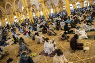 In this photo taken Friday, May 15, 2020, a follower of the Senegalese Mouride brotherhood, an order of Sufi Islam, films with his smartphone as he and others practice social distancing as they attend Muslim Friday prayers at West Africa's largest mosque the Massalikul Jinaan, in Dakar, Senegal. A growing number of mosques are reopening across West Africa even as confirmed coronavirus cases soar, as governments find it increasingly difficult to keep them closed during the holy month of Ramadan. (AP Photo/Sylvain Cherkaoui)