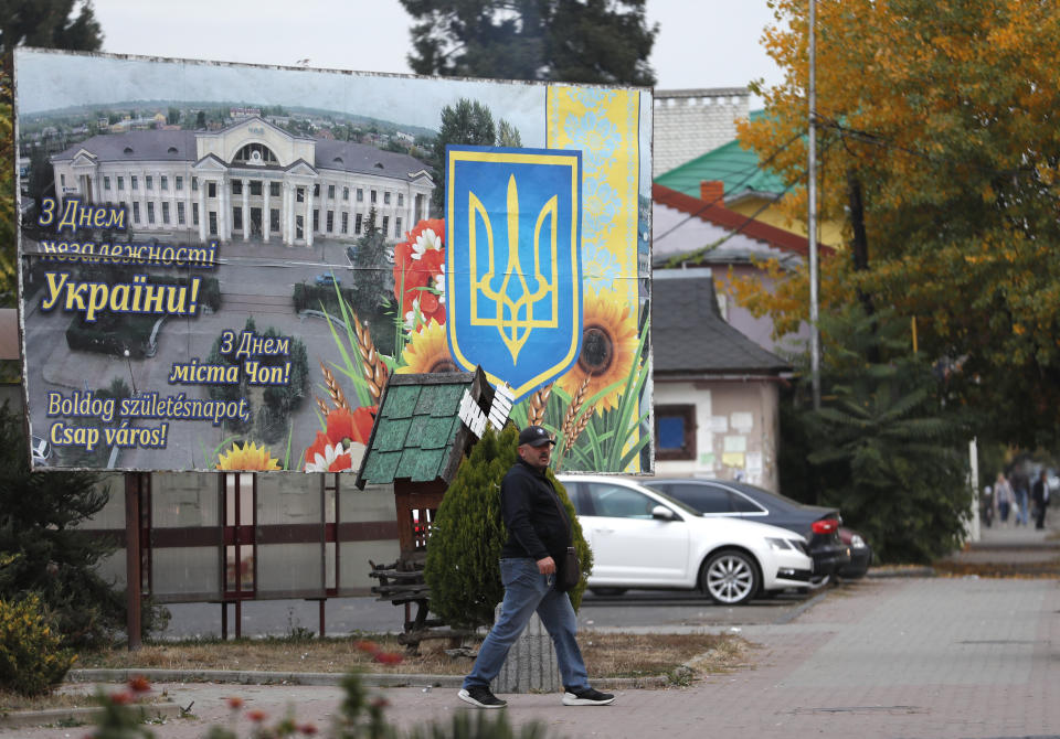 In this Thursday, Oct. 18, 2018 photograph, a man passes by a poster saying "Happy birthday, Chop city!" in Ukrainian, Russian and Hungarian, in Chop, Ukraine. A new education law that could practically eliminate the use of Hungarian and other minority languages in schools after the 4th grade is just one of several issues threatening this community of 120,000 people. Many are worried that even as Ukraine strives to bring its laws and practices closer to European Union standards, its policies for minorities seem to be heading in a far more restrictive direction. (AP Photo/Laszlo Balogh)