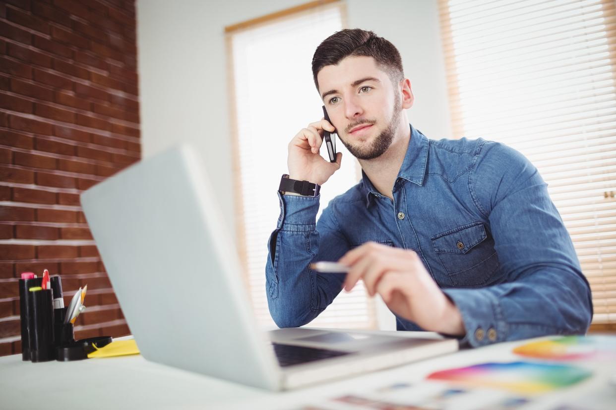 confident young man talking on phone in office