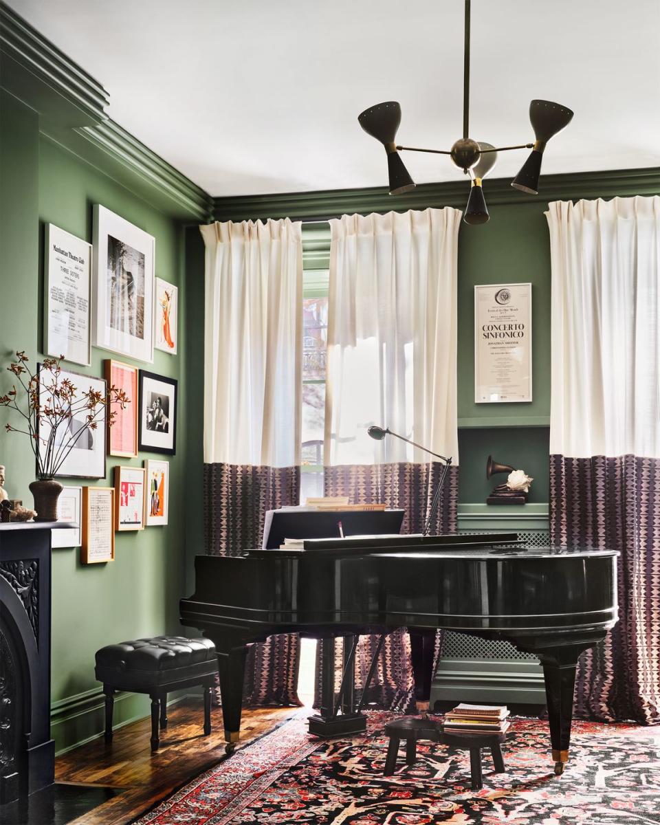 green painted living room corner with art on the walls and a grand piano in the corner