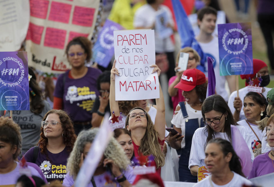 Una mujer muestra un cartel en el que se lee en portugués "dejen de culparnos, juzgarnos, matarnos" durante el Día Internacional de la Mujer en Brasilia, Brasil, el miércoles 8 de marzo 2023. (AP Foto/Gustavo Moreno)