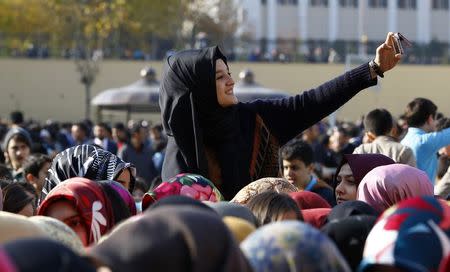 A student of Tevfik Ileri Imam Hatip School takes a "selfie" as she joins others in waiting for the arrival of President Tayyip Erdogan for the opening ceremony in Ankara November 18, 2014. REUTERS/Umit Bektas
