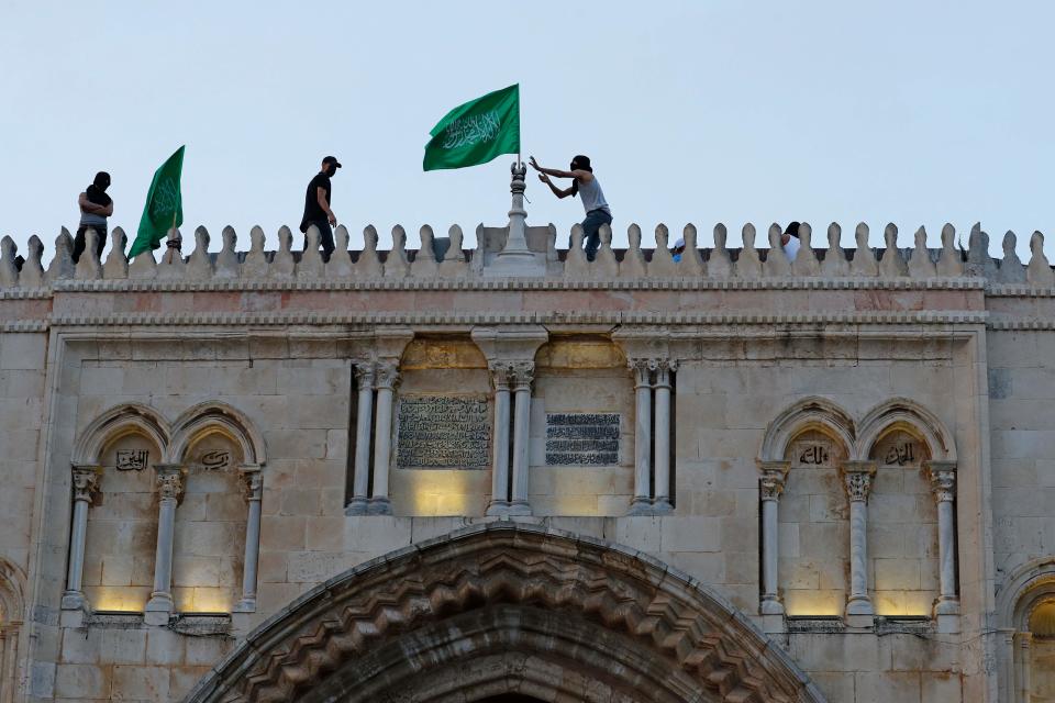 Palestinians place the Hamas movement flag atop al-Aqsa mosque in Jerusalem's Old City on May 10, 2021, ahead of a planned march to commemorate Israel's takeover of Jerusalem in the 1967 Six-Day War.