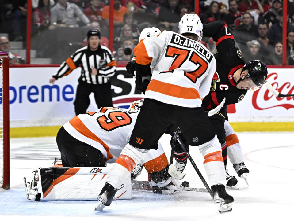 Philadelphia Flyers goaltender Carter Hart (79) makes a save as defenseman Tony DeAngelo (77) tries to keep Ottawa Senators left wing Brady Tkachuk (7) from reaching the puck during the second period of an NHL hockey game, Saturday, Nov. 5, 2022 in Ottawa, Ontario. (Justin Tang/The Canadian Press via AP)