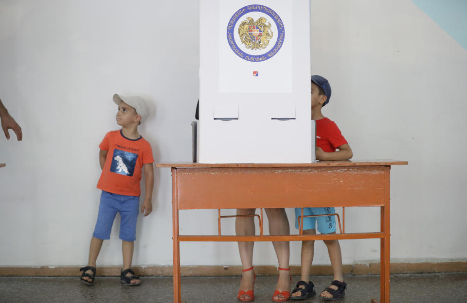 Children stand next to their mother at a polling station during a parliamentary election in Yerevan, Armenia, Sunday, June 20, 2021. Armenians are voting in a national election after months of tensions over last year's defeat in fighting against Azerbaijan over the separatist region of Nagorno-Karabakh. (AP Photo/Sergei Grits)