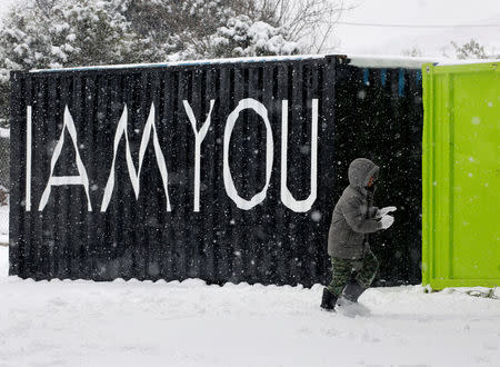 A stranded Syrian refugee boy walks through a snow storm at a refugee camp north of Athens, Greece January 10, 2017.REUTERS/Yannis Behrakis