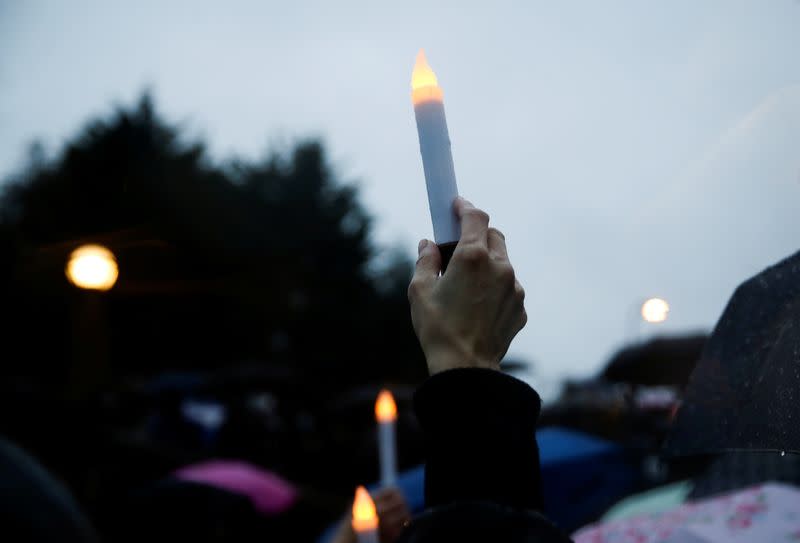 A person holds a battery-powered candle in the rain during a "Stop Asian Hate" rally and vigil to remember the Atlanta shooting victims at Bellevue Downtown Park in Bellevue