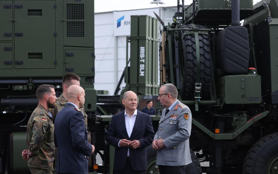 Olaf Scholz, centre, speaks with Gen Carsten Breuer in front of an Iris-T air defence system at the Berlin Air Show