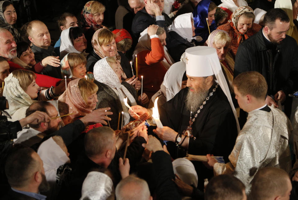 FILE - In this photo taken Saturday, April 7, 2018 head of the Ukrainian Orthodox Church under the Moscow Patriarchate, Metropolitan Onuphrius, lights believers' candles with fire which was delivered to the Ukrainian capital from the Church of the Holy Sepulcher in Jerusalem's Old City, traditionally believed to be the burial place of Jesus Christ, after the ceremony of the Holy Fire, during the Easter service in the Monastery of Caves in Kiev, Ukraine. Tensions over the imminent formation of a Ukrainian Orthodox church independent of Moscow are raising fears that nationalists will try to seize Russian church properties. (AP Photo/Efrem Lukatsky, FILE)