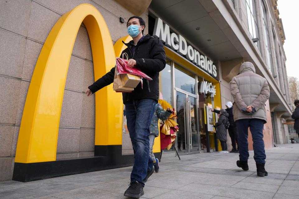 A man carries his take way McDonald's foods as people take order at a machine at a newly opened McDonald's restaurant on Sunday, Dec. 24, 2023.