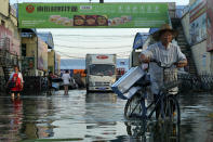 A man carries goods on his bicycle as he walks out of the the Yubei Agricultural and Aquatic Products World in Xinxiang in central China's Henan Province, Monday, July 26, 2021. Record rain in Xinxiang last week left the produce and seafood market soaked in water. Dozens of people died in the floods that immersed large swaths of central China's Henan province in water. (AP Photo/Dake Kang)