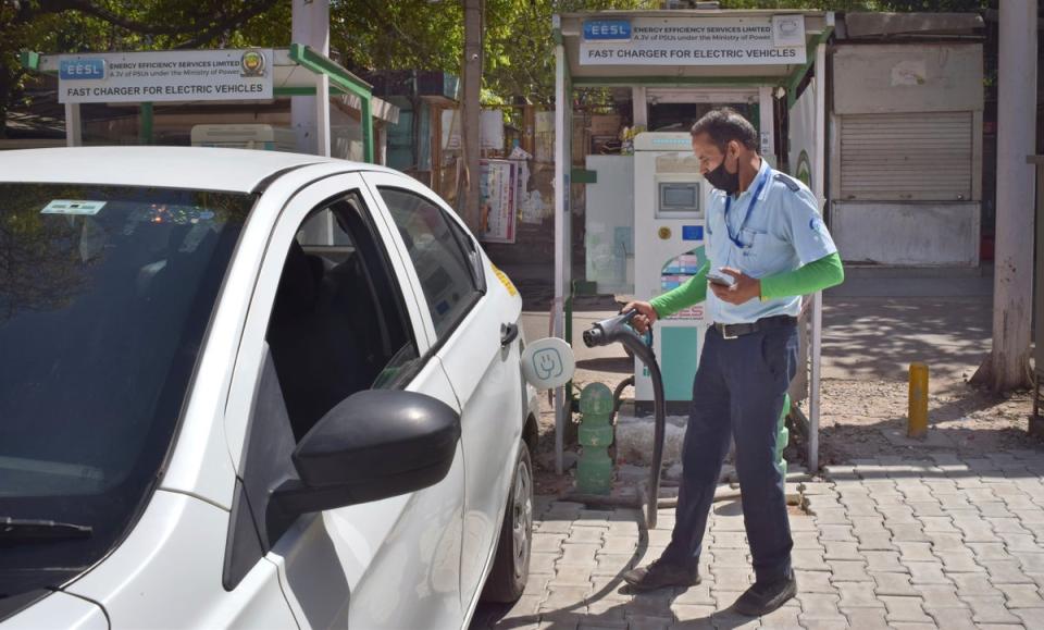 A driver of an electric car charges his vehicle at public charging station in New Delhi, India (AP)