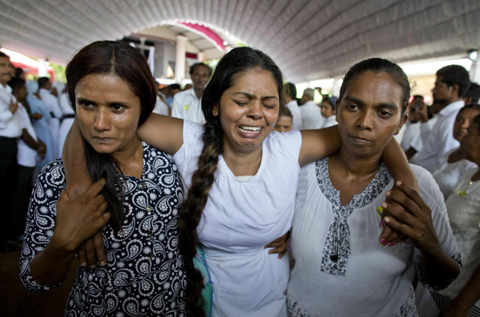 A grieving woman is supported during a funeral service attended by Cardinal Malcolm Ranjith for Easter Sunday bomb blast victims at St. Sebastian Church in Negombo, Sri Lanka, Tuesday, April 23, 2019. (AP Photo/Gemunu Amarasinghe)