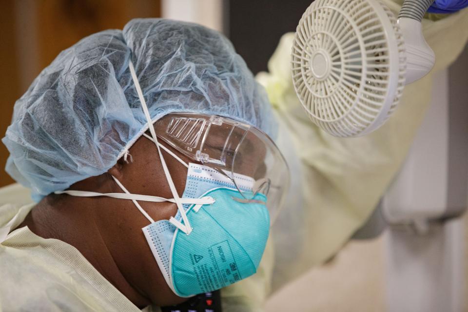 Regina Bolde, a nurse in the yellow level COVID unit at Tallahassee Memorial HealthCare, props her arm up against a hallway wall while she holds a portable fan pointed towards her head as she tries to cool down during her shift Monday, Aug. 23, 2021.