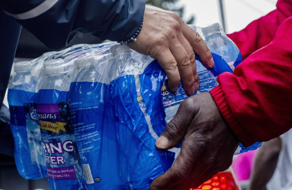 FILE - Volunteers help distribute cases of water bottles at God Household of Faith, Friday, Oct. 29, 2021, in Benton Harbor, Mich. Michigan and local officials have been targeted in a lawsuit over high levels of lead in Benton Harbor's drinking water. The lawsuit, filed this week in federal court, accuses the state and city of "deliberate indifference" in their response to the problem, which began to emerge in 2018. (Nicole Hester/MLIVE.com/The Grand Rapids Press via AP, File)