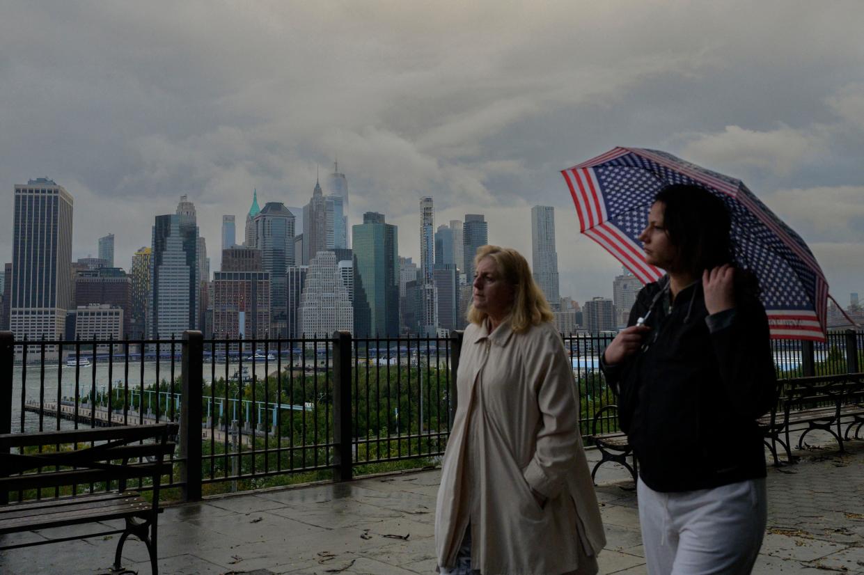 FTSE People walk before the skyline of lower Manhattan on a rainy afternoon on October 5, 2022 in New York City. (Photo by ANGELA WEISS / AFP) (Photo by ANGELA WEISS/AFP via Getty Images)