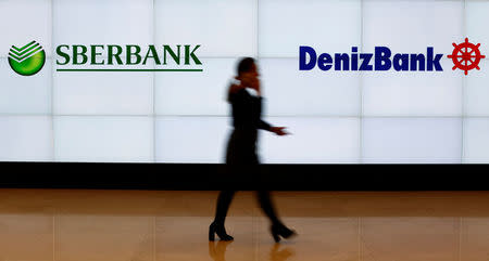 FILE PHOTO: A Denizbank employee walks past by logos of Russia's Sberbank and Turkey's Denizbank at Denizbank headquarters in Istanbul, Turkey March 2, 2016. REUTERS/Murad Sezer/File Photo