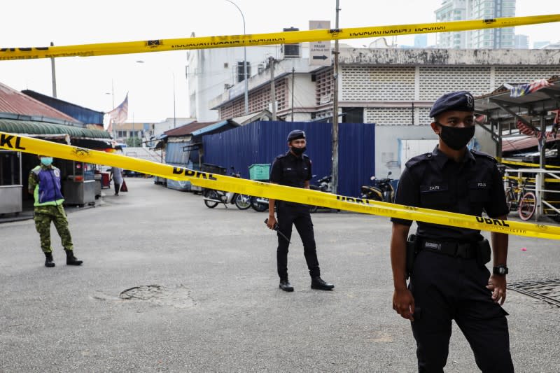 Police officers stand guard at an entrance of a market, during the movement control order due to the outbreak of the coronavirus disease (COVID-19), in Kuala Lumpur