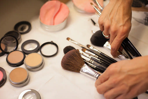 hands reaching for makeup brushes