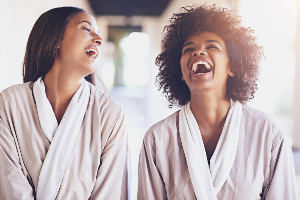 Two women in robes laughing while enjoying the spa. 