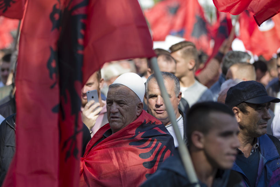 Supporter of Kosovo's opposition Self-Determination party draped with national Albanian flag marches during a protest toward Skanderbeg Square on Saturday, Sept. 29, 2018, in Kosovo capital Pristina. Thousands of people in Kosovo are protesting their president's willingness to include a possible territory swap with Serbia in the ongoing negotiations to normalize relations between the two countries.(AP Photo/Visar Kryeziu)