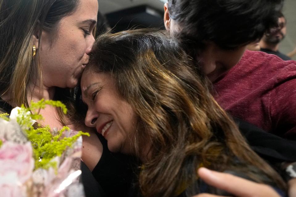 A mother is embraced by her children at Brasilia Air Base (AP)