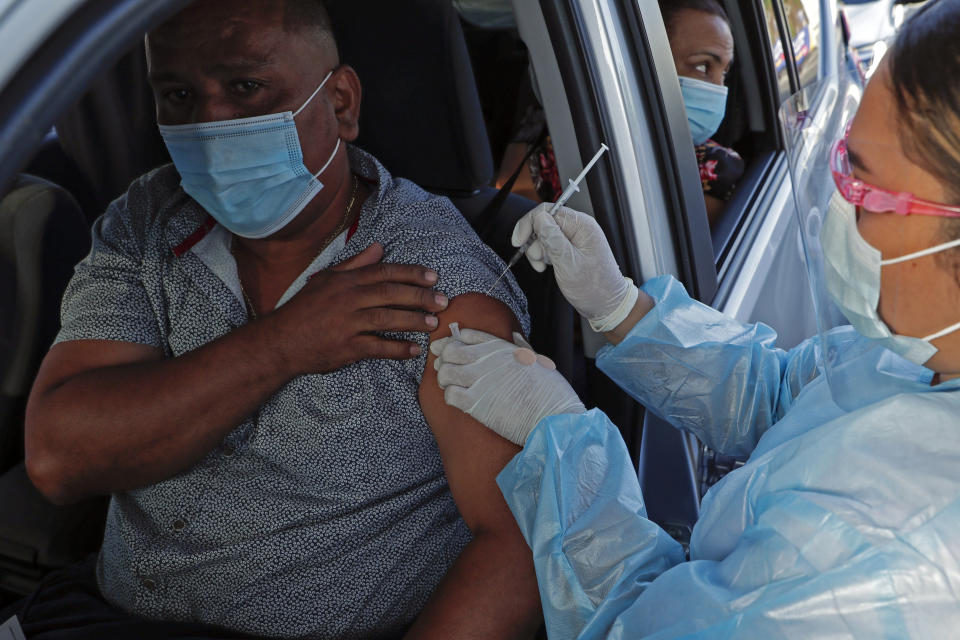 Un hombre recibe la primera dosis de la vacuna AstraZeneca contra el COVID-19 en un automóvil en el estadio de fútbol Rommel Fernández de la Ciudad de Panamá, el jueves 22 de abril de 2021. Panamá volvió a permitir desde el lunes 10 de mayo la celebración de congresos, foros y convenciones con aforo máximo de 25% en medio de un ligero repunte de contagios. (AP Foto/Arnulfo Franco)