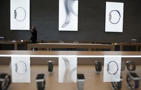 A man uses a mobile phone as he walks between displays of Apple Watch inside an Apple Store in Berlin April 10, 2015. REUTERS/Stefanie Loos