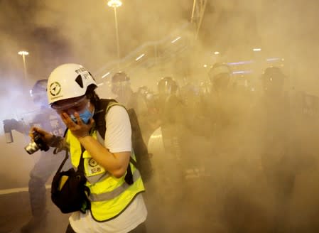 A journalist covers her face after police officers fired tear gas toward anti-extradition bill protesters during a protest in Hong Kong